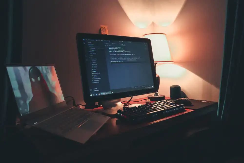 A developer's dark workspace with game code on multiple screens